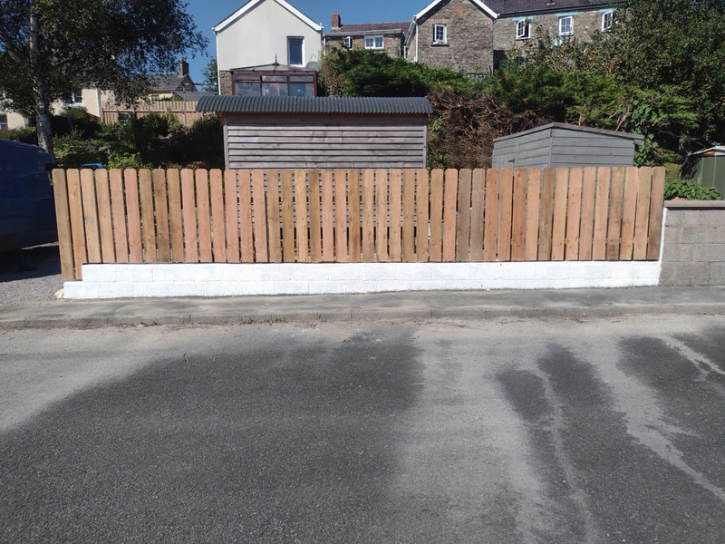 a handmade wooden fence along a driveway