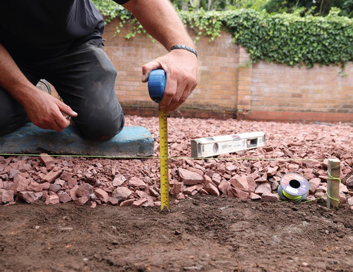 a person using a measuring tape to measure the depth of subbase